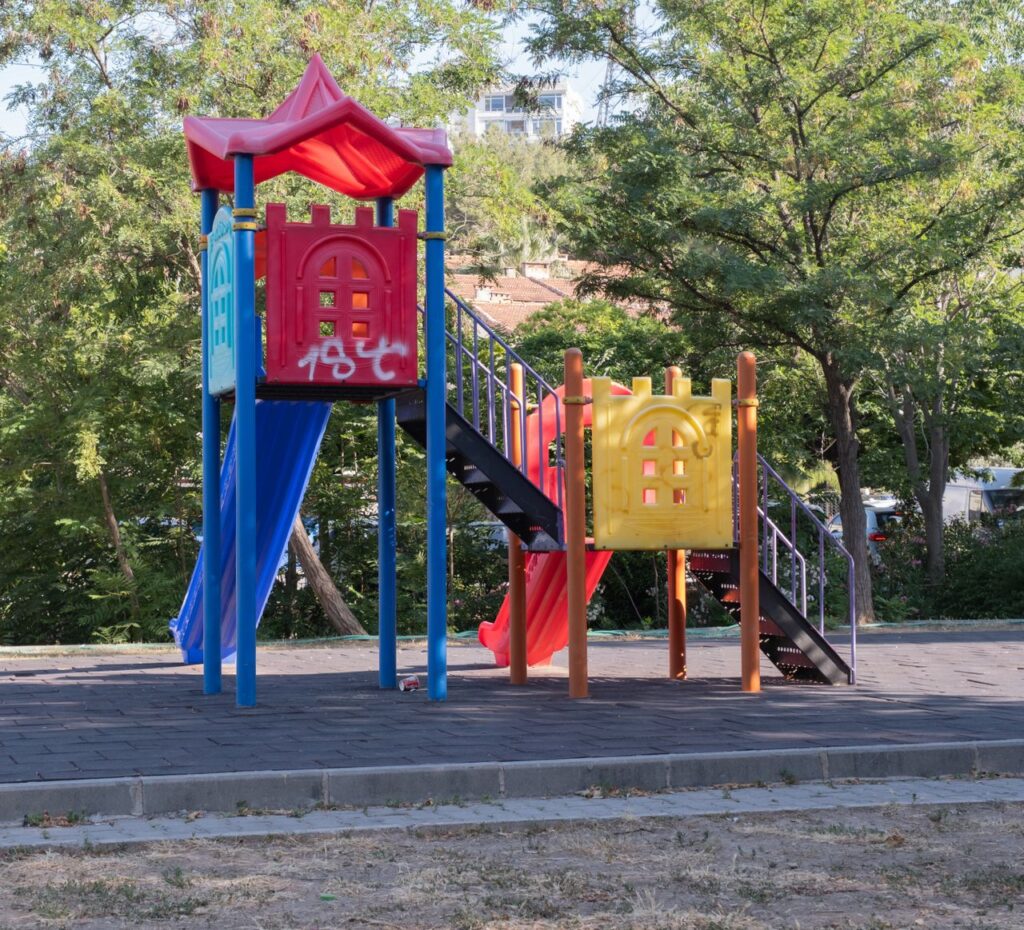 Vibrant playground equipment in a sunny İzmir park, ideal for kids' outdoor activities.